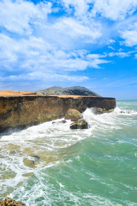 a beach scene with waves crashing against a cliff