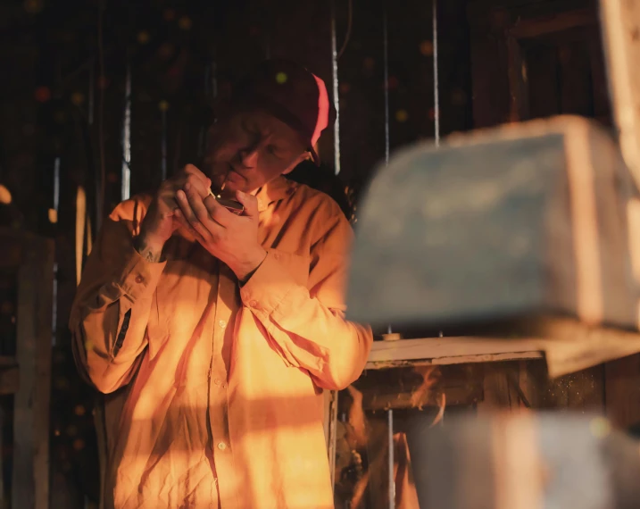 a man wearing an orange jacket eating food in a barn