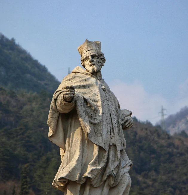 the statue of saint peter stands in front of a mountainous hill