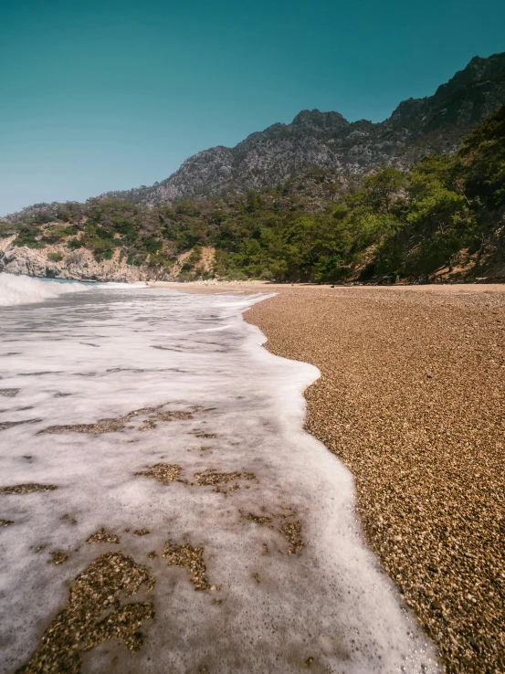 water and sand at the beach next to mountains