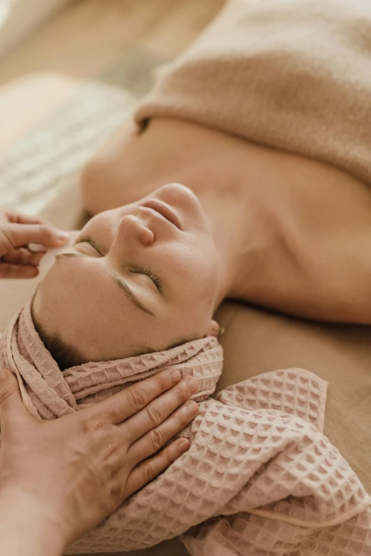 a woman who is laying down with her head on a pillow and a person holding it over the back of her face