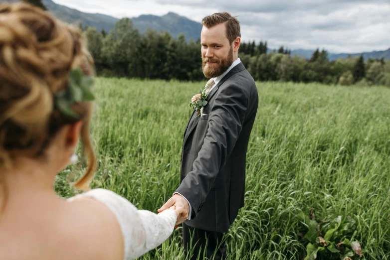 the groom is looking at his bride in the grass