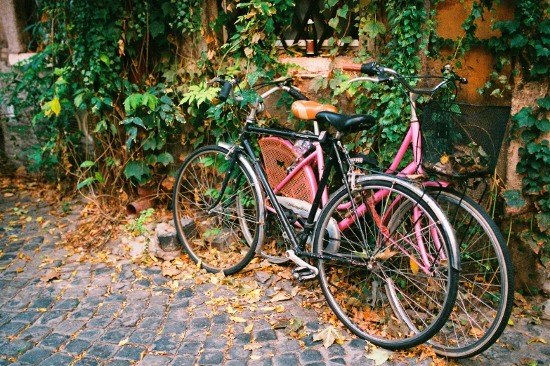 the pink bicycle is  to the brick fence