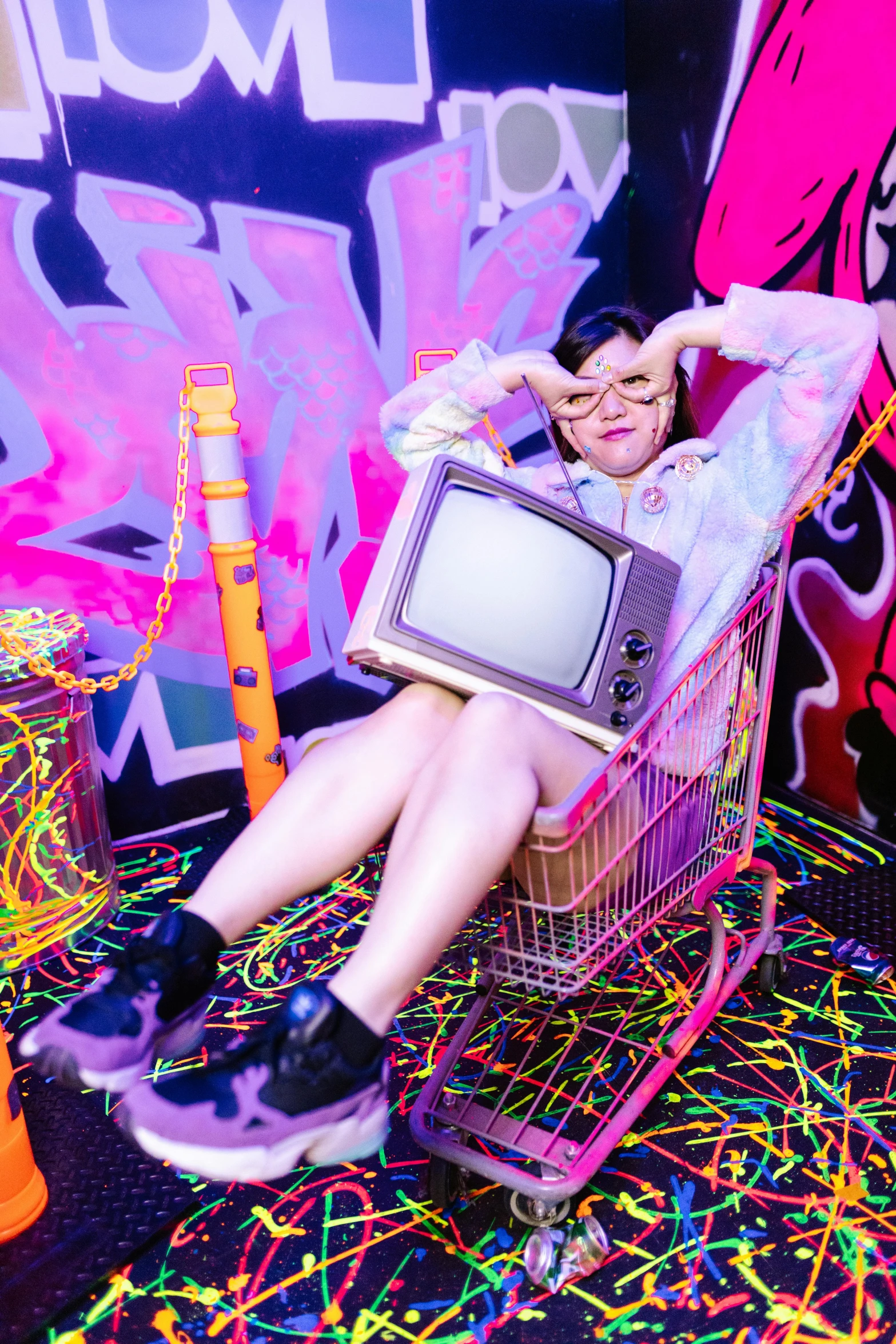 a woman sits in a shopping cart and holds a tv monitor