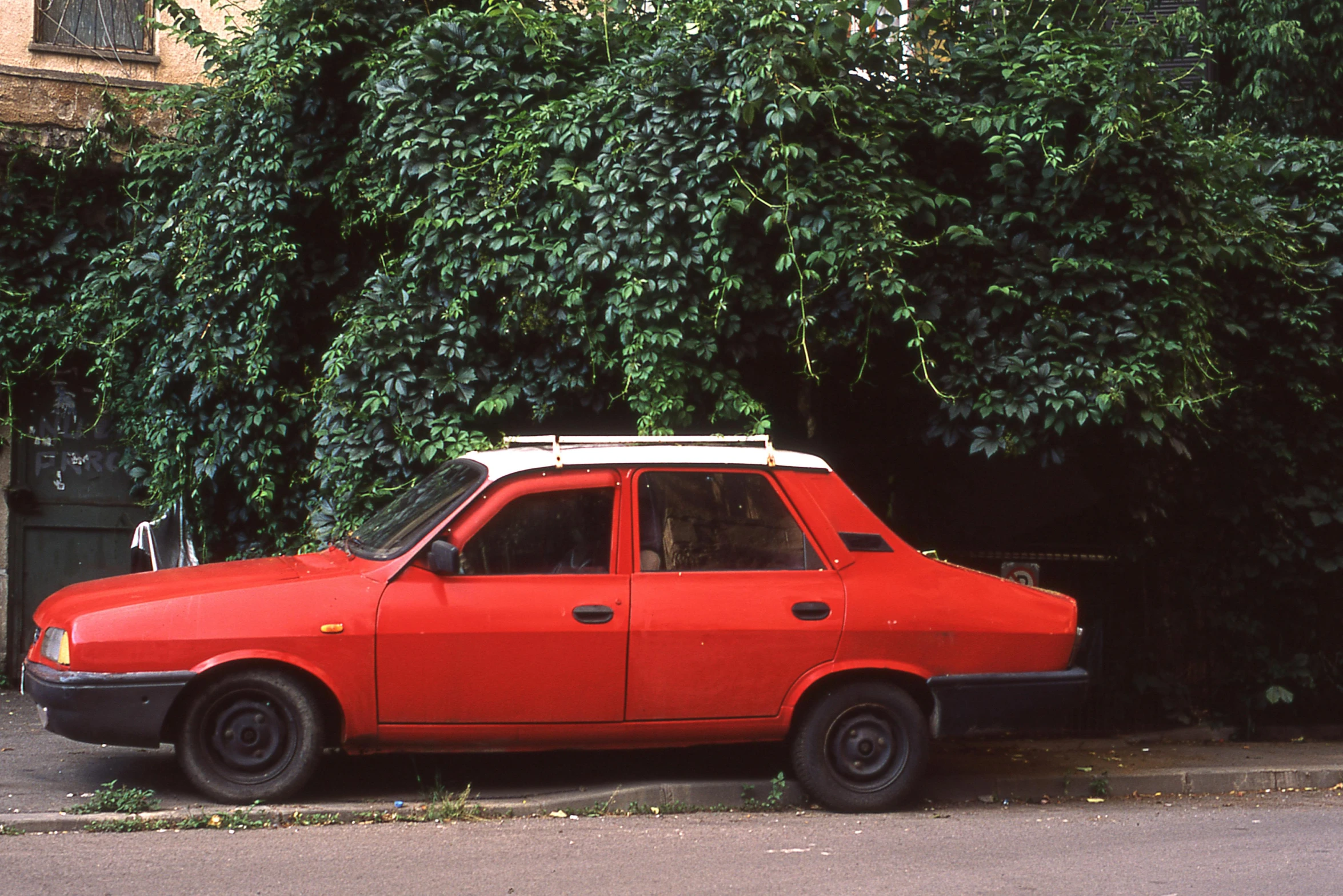 an old red car parked by a bush