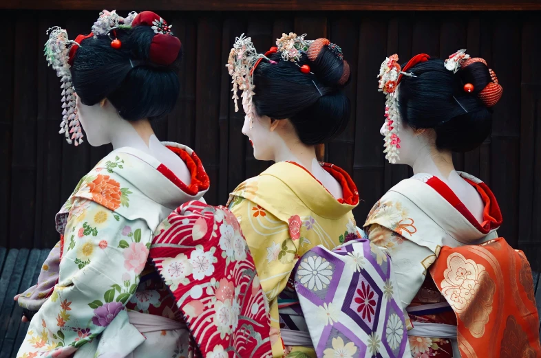 three women dressed in geisha are standing in line