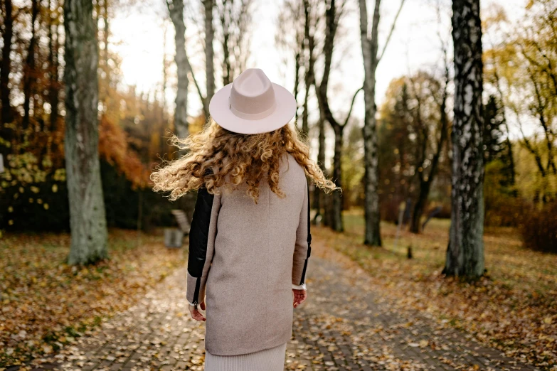 a woman wearing a white hat is standing on a path