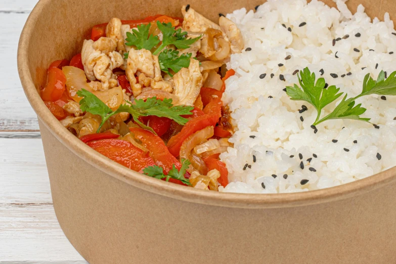 rice, chicken and vegetables in a bowl with a sprig of parsley