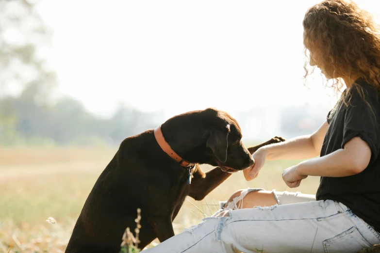 a woman holds the paw of a puppy who is sitting next to her