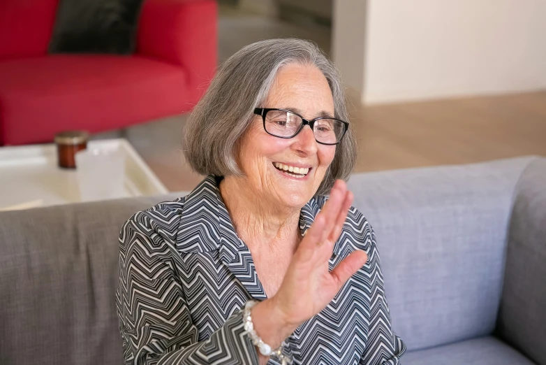 an old woman sitting on top of a couch clapping