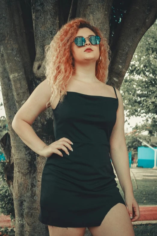 a woman wearing glasses standing in front of a tree