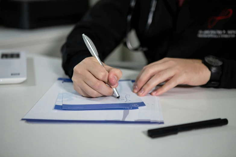 a person writing on paper with their pen