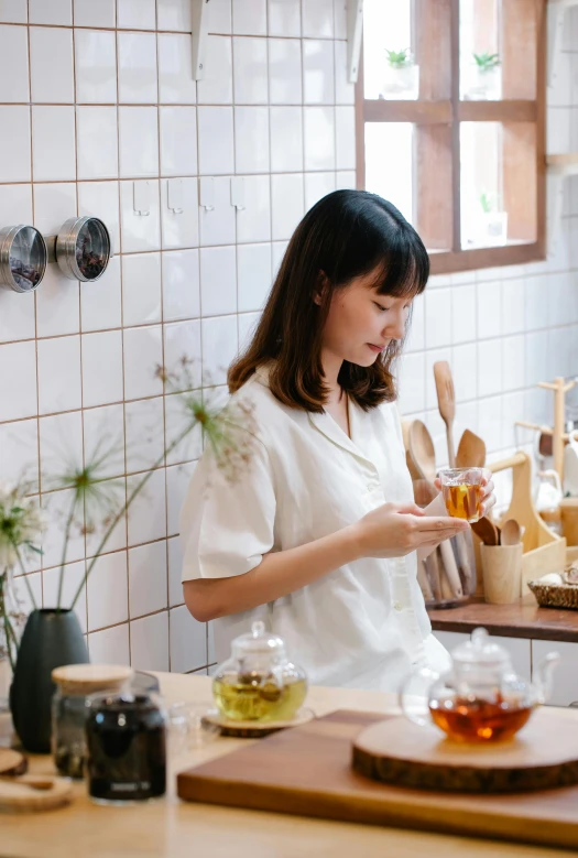 a woman standing over a counter with a cup