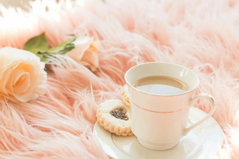 a cup of coffee next to a rose