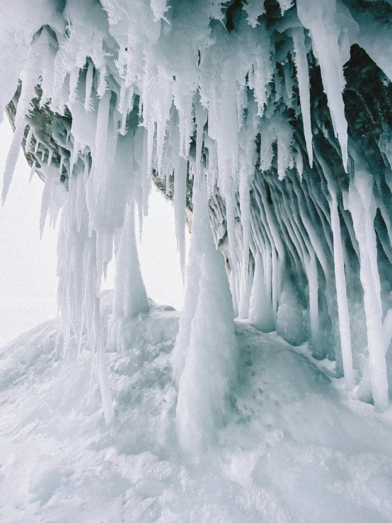 large ice formations are hanging off a steep side of a mountain