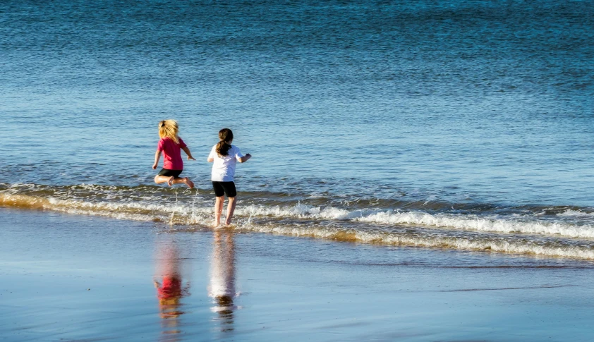 two people walking on the shore along a river