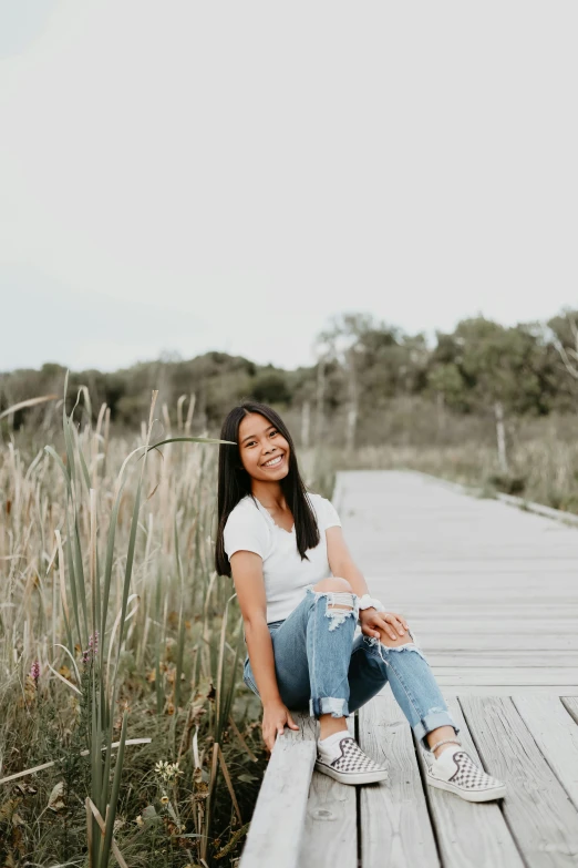 a girl sitting on a pier in the sun