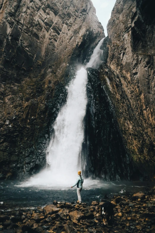 there is a man standing in the water next to a waterfall