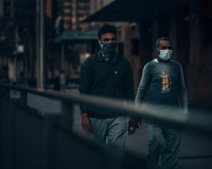 two men are walking down the street with masks on