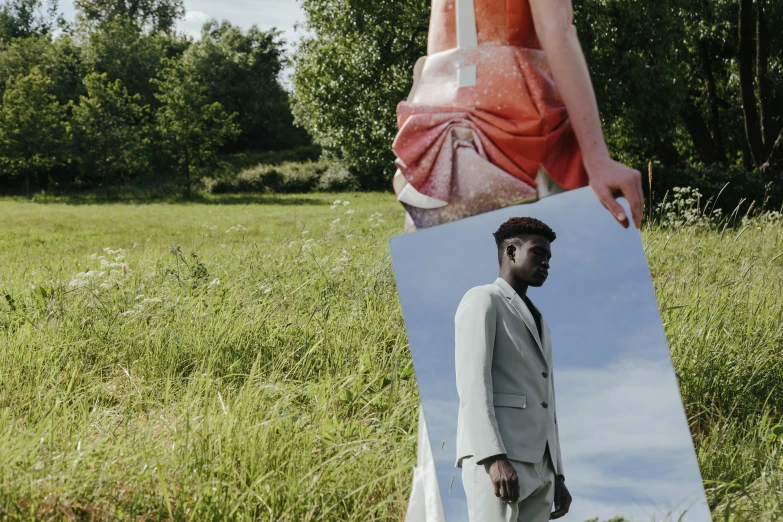 a person is reflected in a mirror in a grassy field