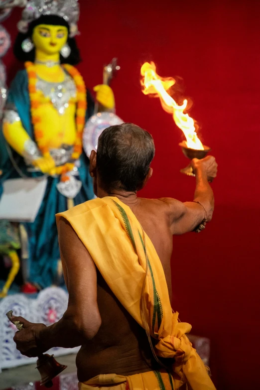 the back view of a man in yellow cloth holding fire torch