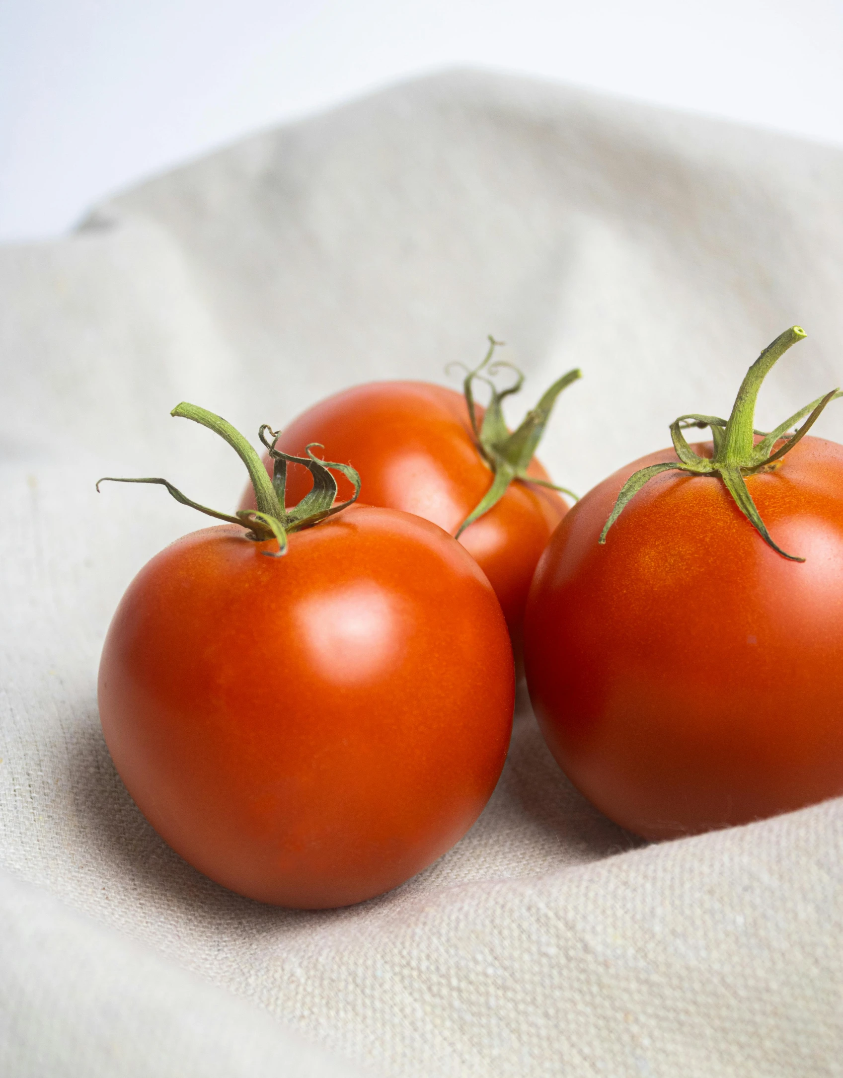 three small tomatoes are sitting on the white sheet