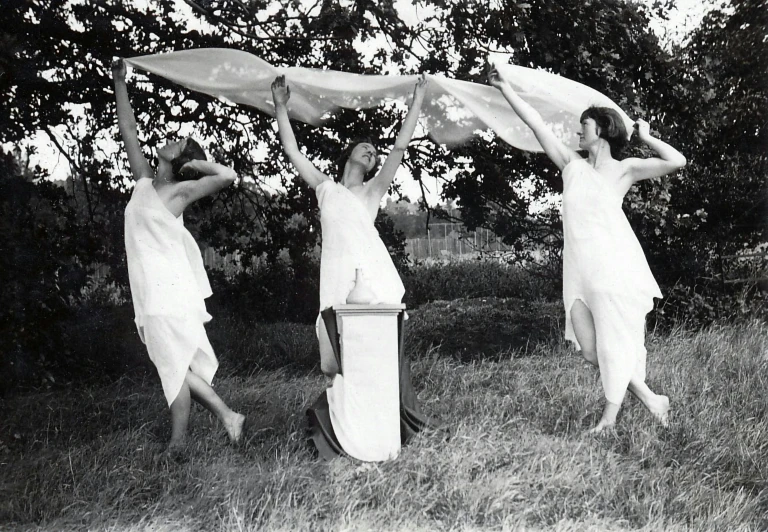 three women holding towels are walking in the grass