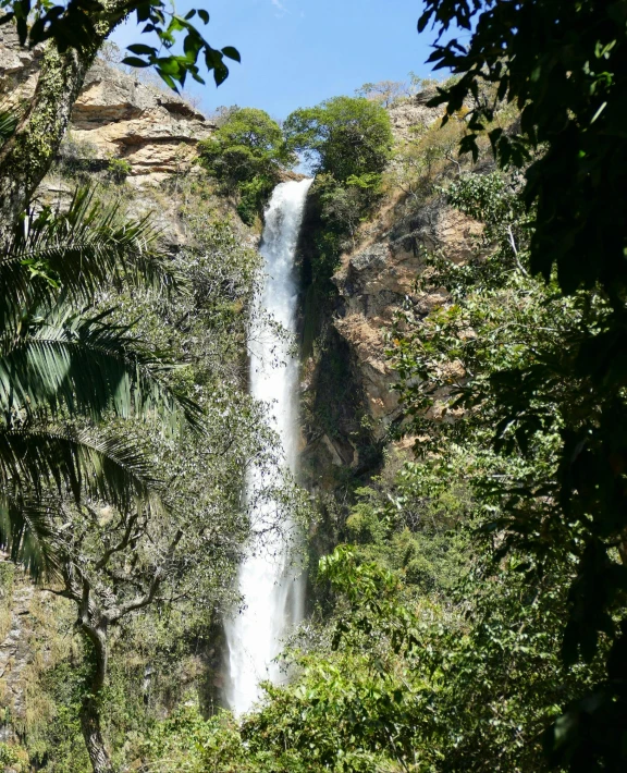 the view of a waterfall through some trees