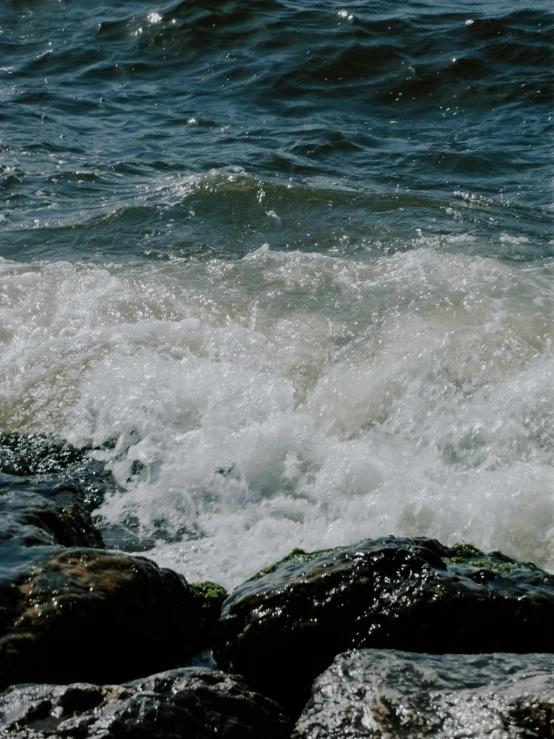 a wave crashing in front of some rocks