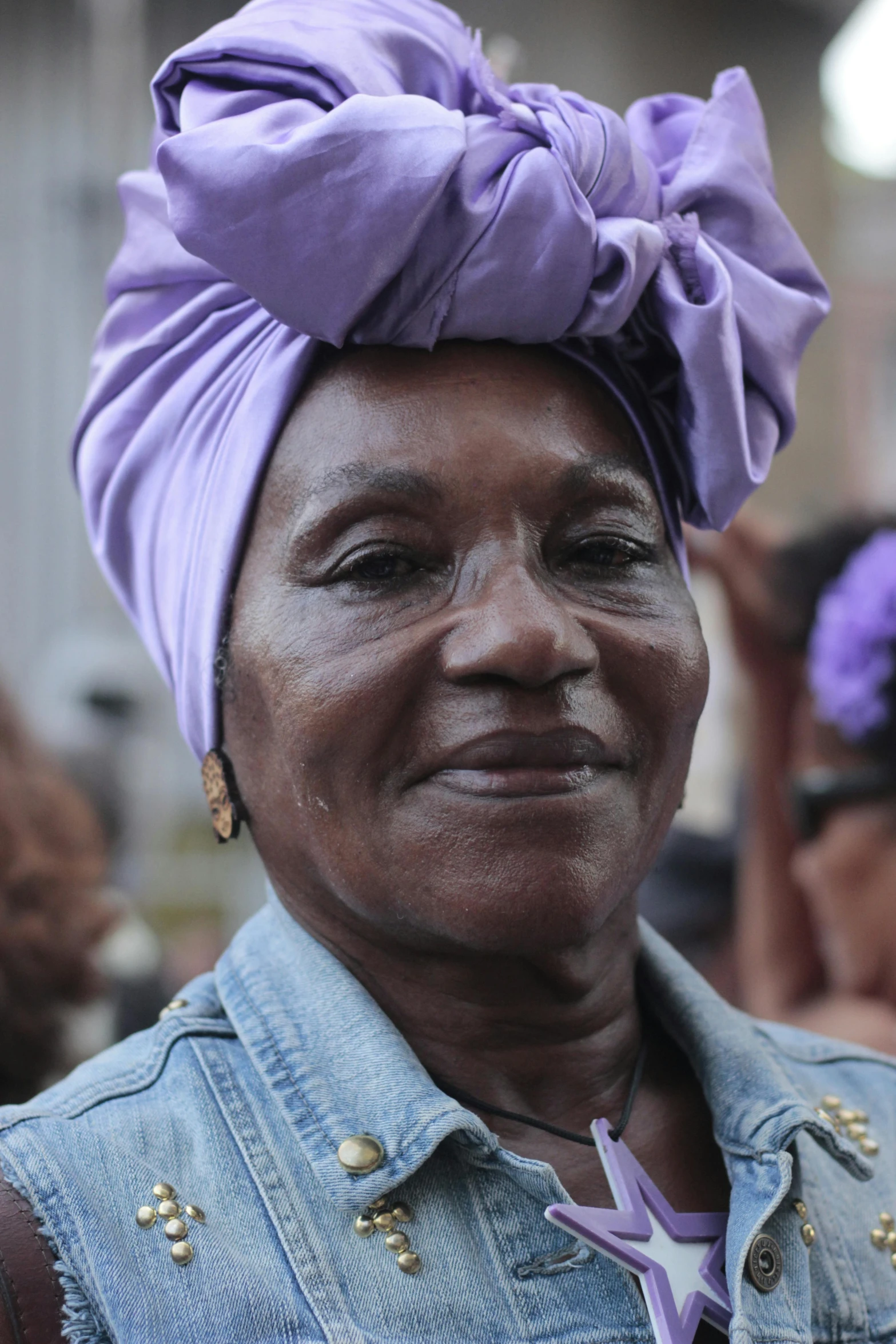 an older woman in a blue jacket and a purple scarf around her head