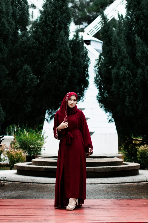 a woman wearing a red abana walking through the park