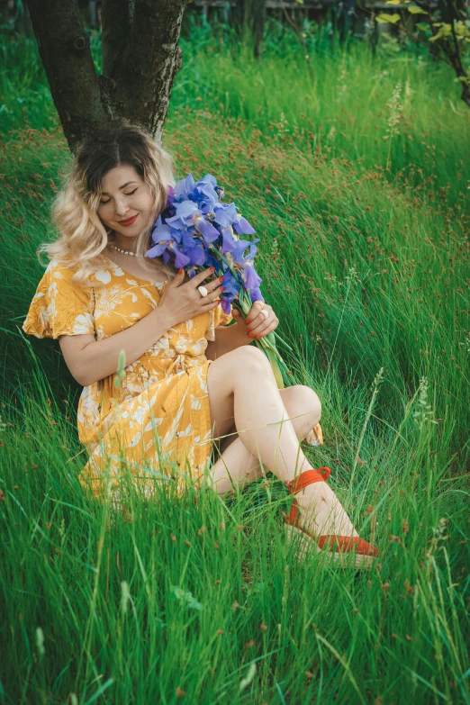 a woman sitting in a field with a bouquet of flowers