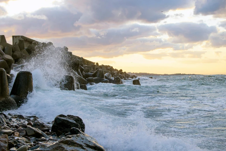 large rocks and waves crashing over them near the shore