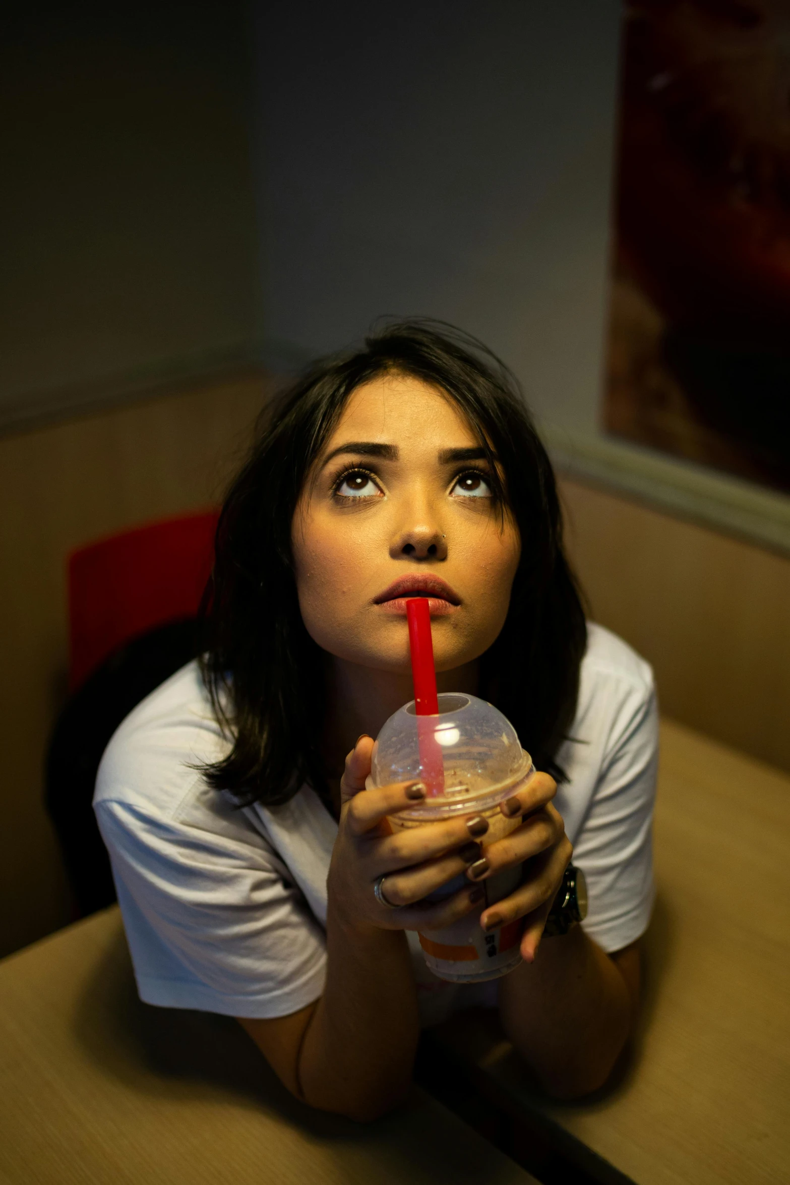 a woman sitting at a table holding a drink