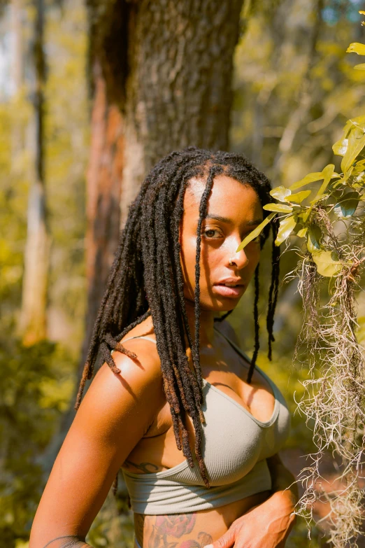 a woman standing next to a tree in the woods