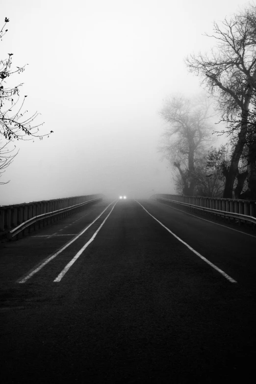 a highway with a car coming through the fog