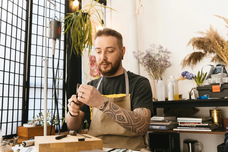 man sitting at table with tattooed arms and a tote bag looking at the contents