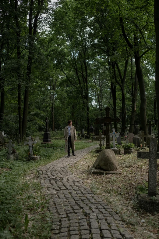 the man is walking down the bricked pathway through the cemetery