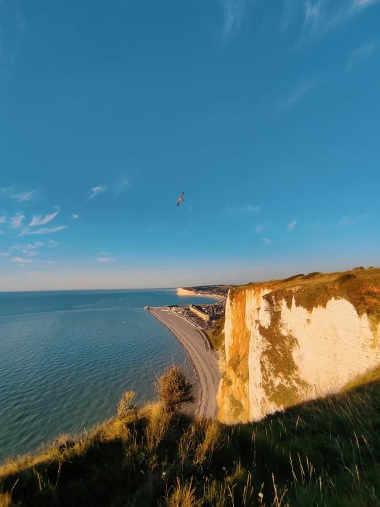 a view of a cliff next to a lake with a beach in the background