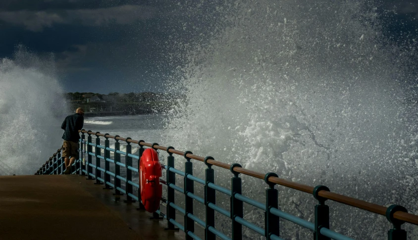 a person standing on a ledge watching waves crashing