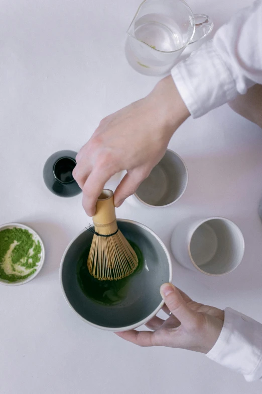 a woman whisk green tea in black cups