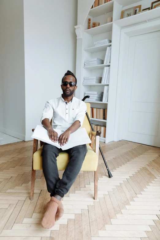 a man with eye glasses sitting in a yellow chair