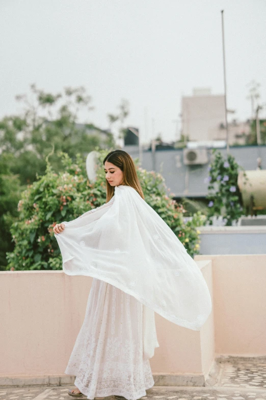 a woman in white dress holding up a large white cloth