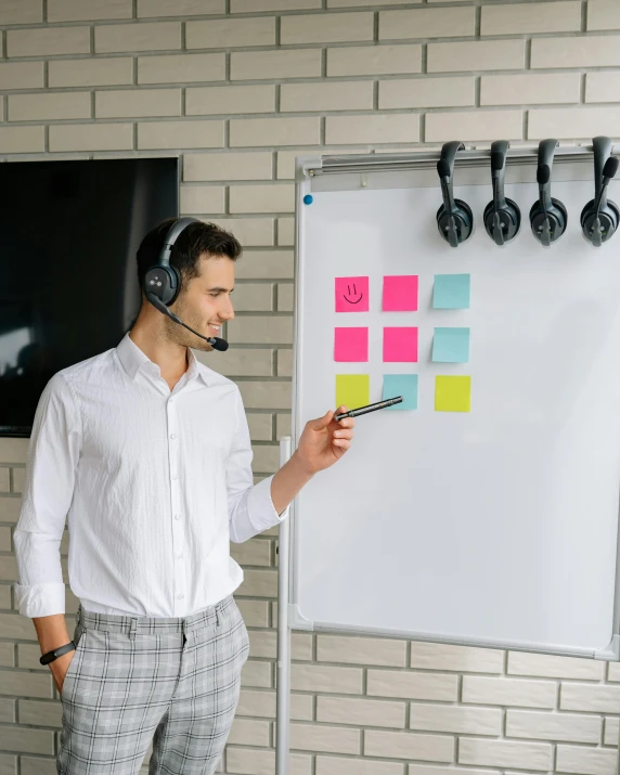 a man standing in front of a white board with headphones