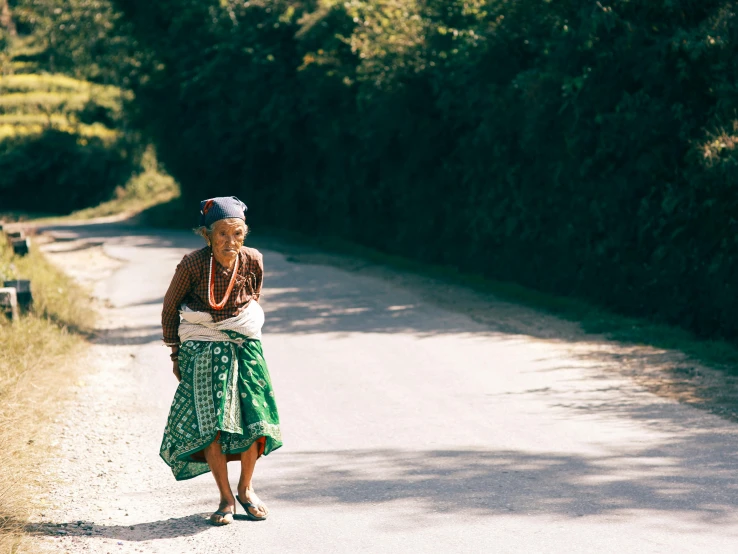 a woman standing on the side of a road in front of trees