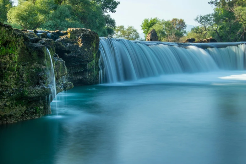 a waterfall in a natural setting with blue water