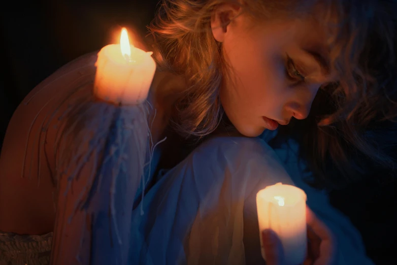 a woman is holding two candles with both hands