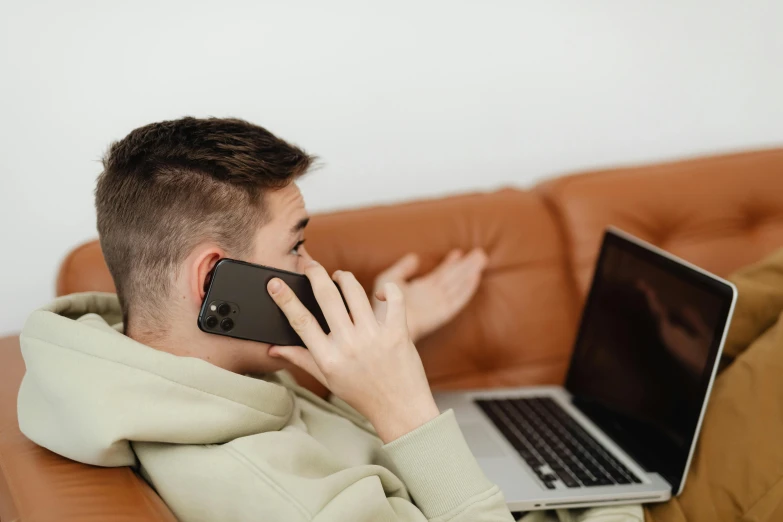 young man sitting on a sofa while using his cell phone