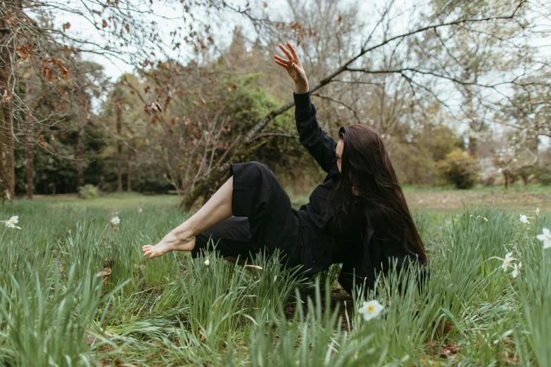 a woman in black laying on the ground in the grass