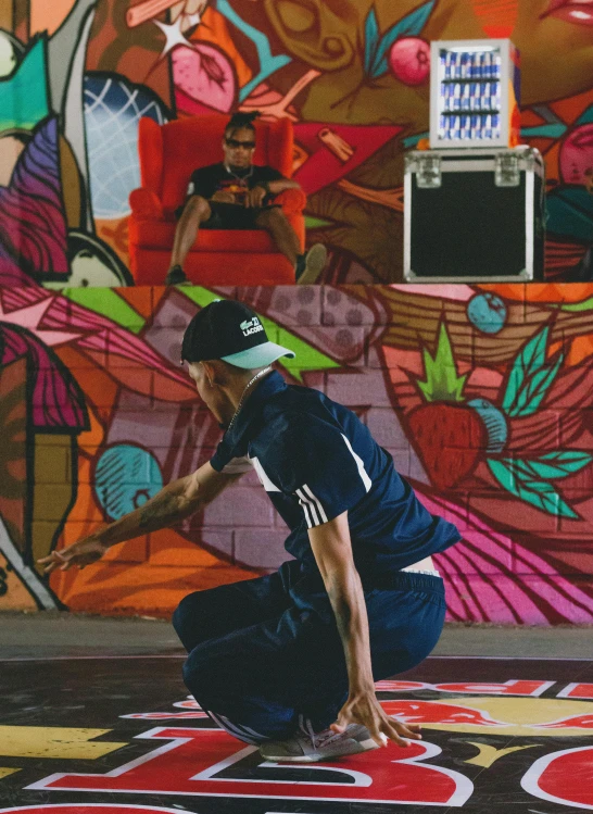 a man sitting on the ground while painting a mural